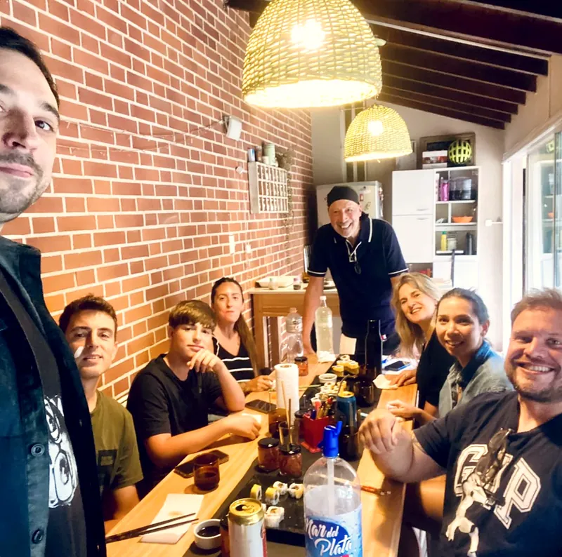 Selfie del grupo sonriendo alrededor de la mesa, con Carlos al fondo